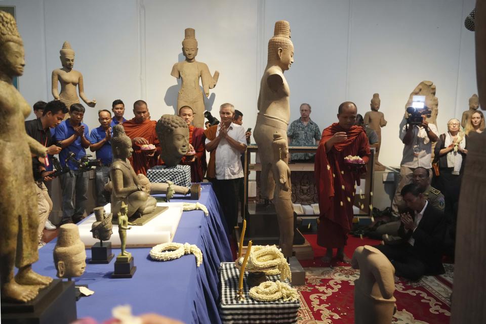 Cambodian Buddhist monks blessing with holy water onto the artifact statues as they return from U.S to Cambodia, during an official ceremony at the Cambodian National Museum in Phnom Penh Cambodia, Thursday, July 4, 2024. Cambodia on Thursday officially organized a welcome ceremony for the arrival of more than a dozen rare Angkor era sculptures from New York's Metropolitan Museum of Art that were tied to an art dealer and collector accused of running a huge antiquities trafficking network out of Southeast Asia. (AP Photo/Heng Sinith)