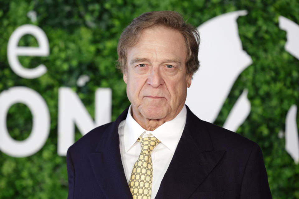 John in a suit with a patterned tie on a backdrop with leaf patterns