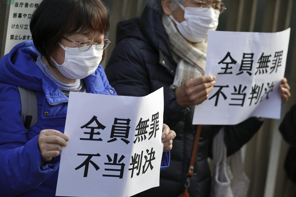 Yoshiko Furukawa, left, and Etsuko Kudo, right, supporters of the plaintiff hold a cloth sign that reads "All not guilty, Unfair judgment," outside of the Tokyo High Court in Tokyo Wednesday, Jan. 18, 2023. The court on Wednesday found three former executives of Tokyo Electric Power Company not guilty of negligence over the 2011 Fukushima nuclear meltdowns and subsequent deaths of more than 40 elderly residents during their forced evacuation. (AP Photo/Eugene Hoshiko)