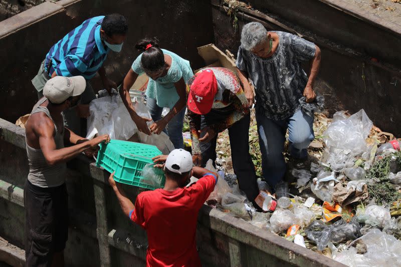 People search for food at a garbage container during the closing hour at the Coche wholesale market amid coronavirus (COVID-19) disease outbreak in Caracas