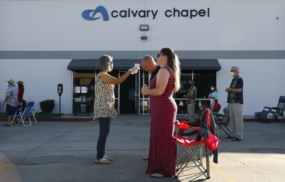 Worshipers John and Kimberly Wellons, right, get their temperature taken by Julie Hamilton at Calvary Chapel Temecula Valley.