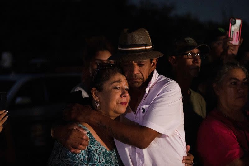 Foto del lunes de Christine y Michael Ybarra abrazándose en el lugar de San Antonio, Texas, donde se encontraron decenas de migrantes muertos dentro de un trailer