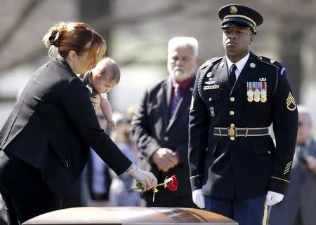 FILE PHOTO: Widow Alexandra McClintock (L) holds her son Declan while placing a rose on the casket of her husband U.S. Army Sergeant First Class Matthew McClintock, who was killed in action in Afghanistan in January, at Arlington National Cemetery in Virginia March 7, 2016. REUTERS/Gary Cameron/File Photo