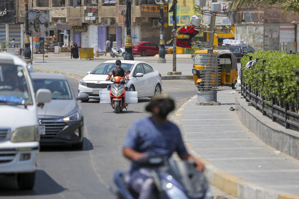 People navigate a street of Sadr City, in Baghdad, Iraq, Thursday, Aug. 4, 2022. Residents of the impoverished Baghdad suburb say they they support Muqtada al-Sadr, an influential Shiite cleric who called on thousands of his followers to storm Iraq's parliament. (AP Photo/Anmar Khalil)