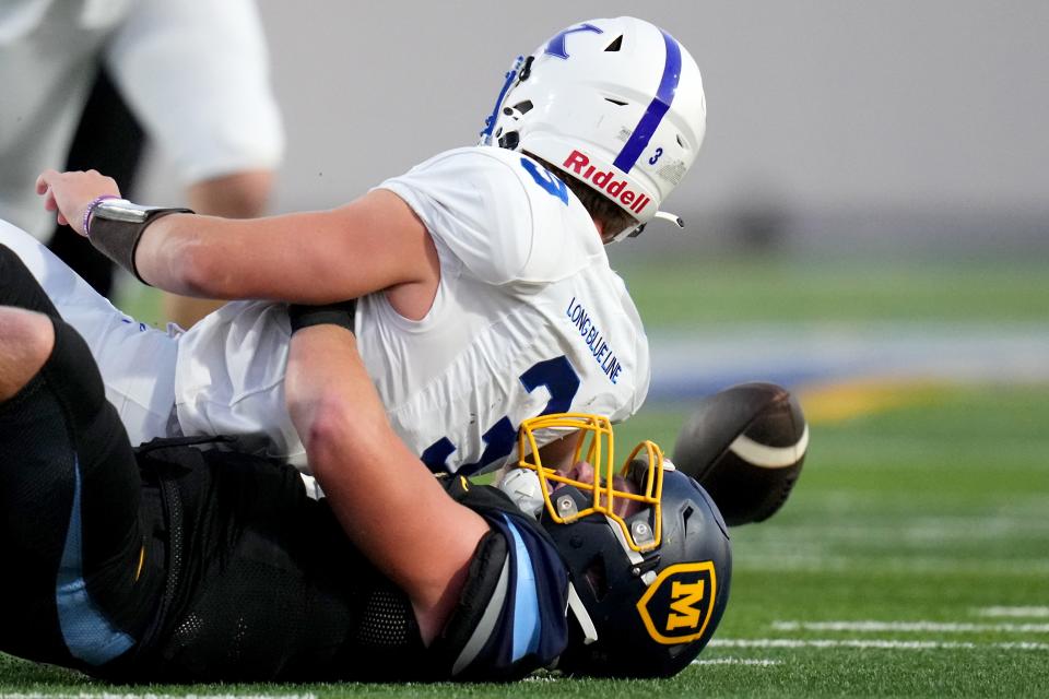 Moeller Crusaders linebacker Kyler Paul (40) sacks and forces a fumble of St. Xavier quarterback Daniel Vollmer (3) in the first half of their high school football game Friday, Sept. 15, 2023, at Welcome Stadium in Dayton, Ohio.