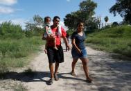Honduran migrants Marvin Madrid and his new wife Dexy Maldonado walk along the Rio Bravo near an encampment in Matamoros