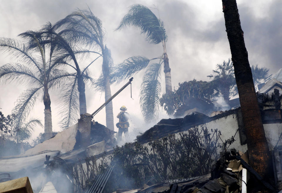 <p>A firefighter stands under windswept palm trees as he hoses down smoldering debris in Ventura, Calif., Tuesday, Dec. 5, 2017. (Photo: Daniel Dreifuss via AP) </p>