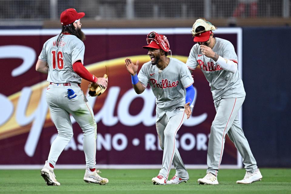 Philadelphia Phillies center fielder Johan Rojas (center) celebrates on the field with right fielder Nick Castellanos (8) and left fielder Brandon Marsh (16) after defeating the San Diego Padres Friday at Petco Park in San Diego.