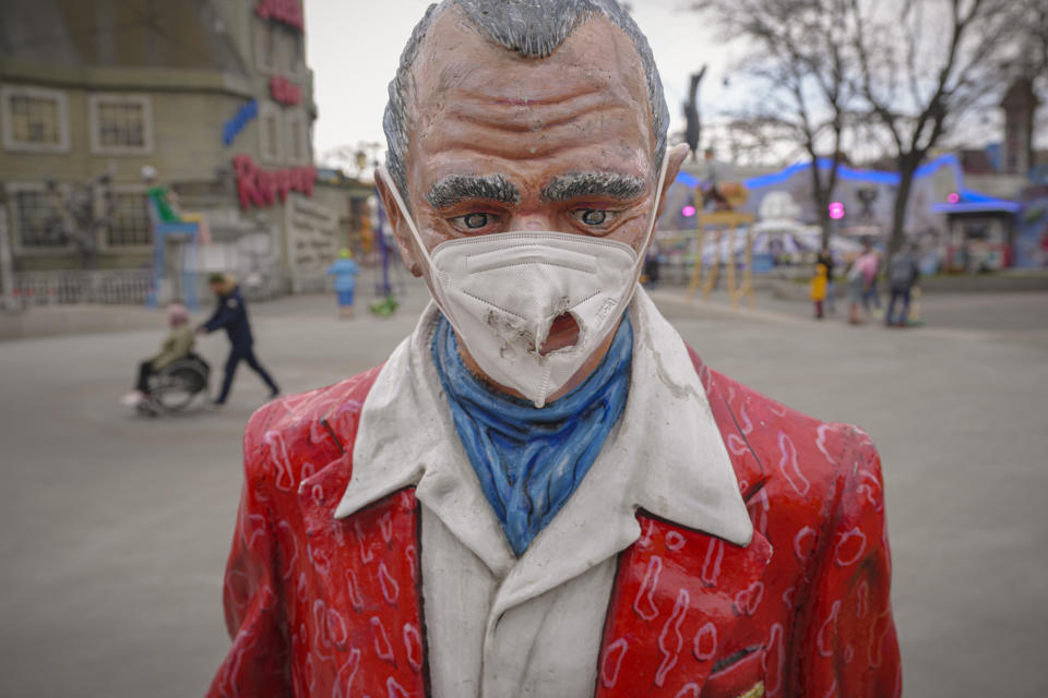 A damaged face mask is placed on a statue at the Prater amusement park in Vienna, Austria, Sunday, Nov. 21, 2021. The Austrian government announced a nationwide lockdown that will start Monday and comes as average daily deaths have tripled in recent weeks and hospitals in heavily hit states have warned that intensive care units are reaching capacity.(AP Photo/Vadim Ghirda)