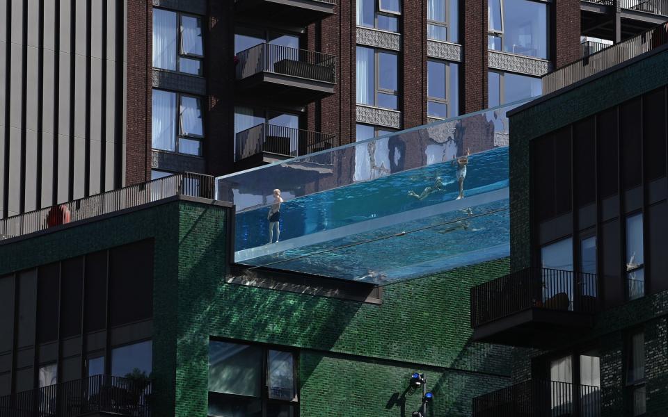 People relax during hot weather at the Embassy Gardens Sky Pool, a transparent acrylic swimming pool suspended between two buildings in the VNEB development - Reuters