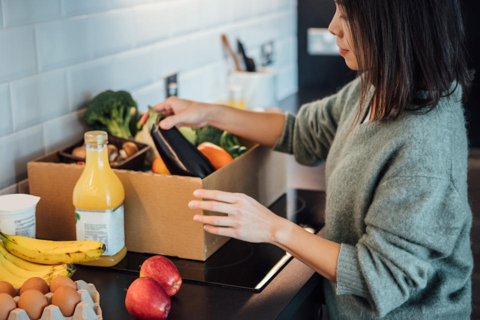 Woman unpacking groceries from a delivery box in a kitchen