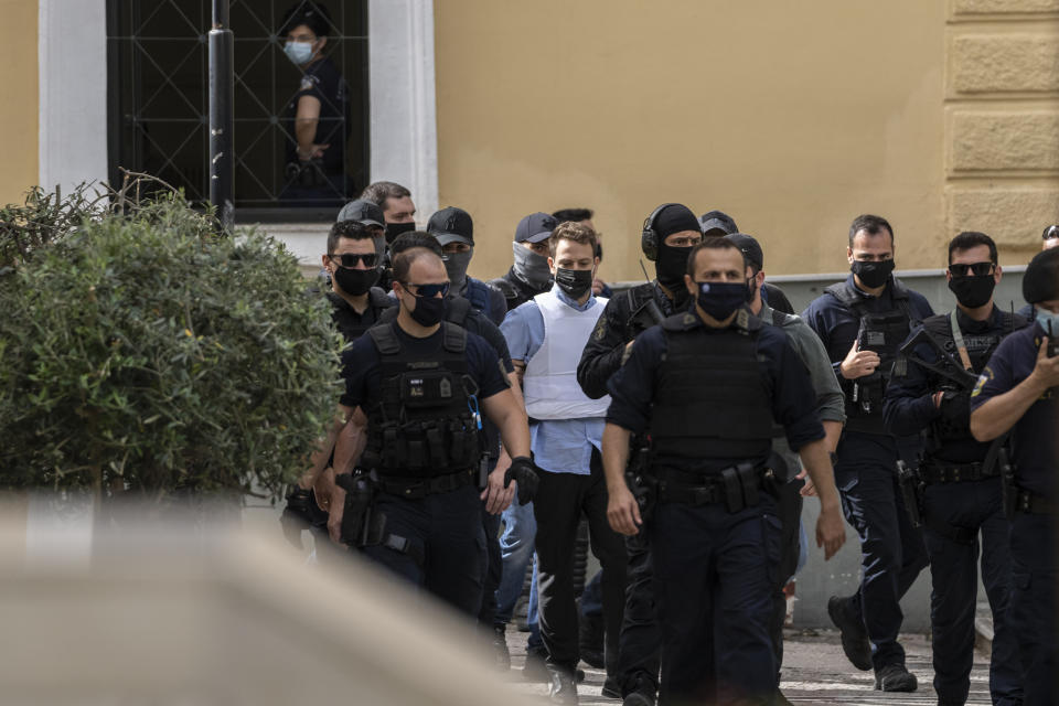 Helicopter pilot Babis Anagnostopoulos, center in white vest, escorted by police officers arrives to the prosecutor's office at a court to give evidence, in Athens, Tuesday, June 22, 2021. Anagnostopoulos was charged last Friday with the murder of his British-Greek wife, Caroline Crouch, 20, whose death he had initially claimed was caused by burglars during a brutal invasion of their home on the outskirts of Athens. (AP Photo/Petros Giannakouris)