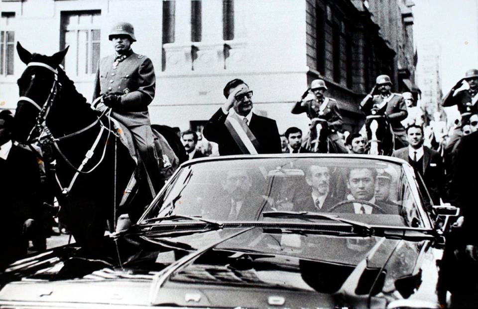 Chilean President Salvador Allende salutes from an open vehicle as General Augusto Pinochet rides on horseback alongside him in Santiago, in May 1972 (Associated Press)