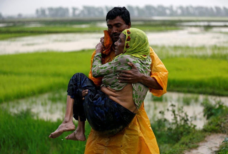 A local man carries an old Rohingya refugee woman as she is unable to walk after crossing the border, in Teknaf, Bangladesh, on Sept. 1, 2017.