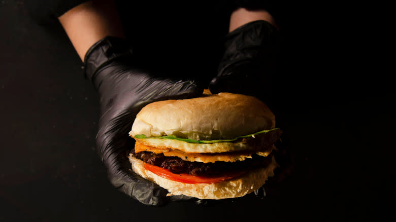 black gloved hands holding burger