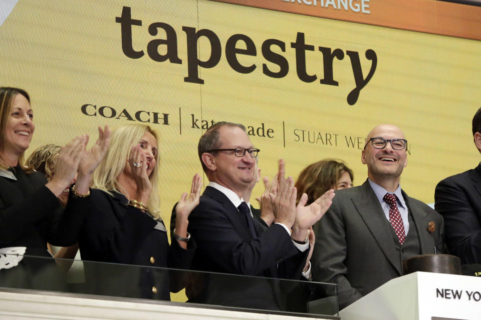 Tapestry Inc. CEO Victor Luis, right, home to Coach, Kate Spade and Stuart Weitzman brands, is applauded as he rings the New York Stock Exchange opening bell, Tuesday, Oct. 31, 2017. (AP Photo/Richard Drew)