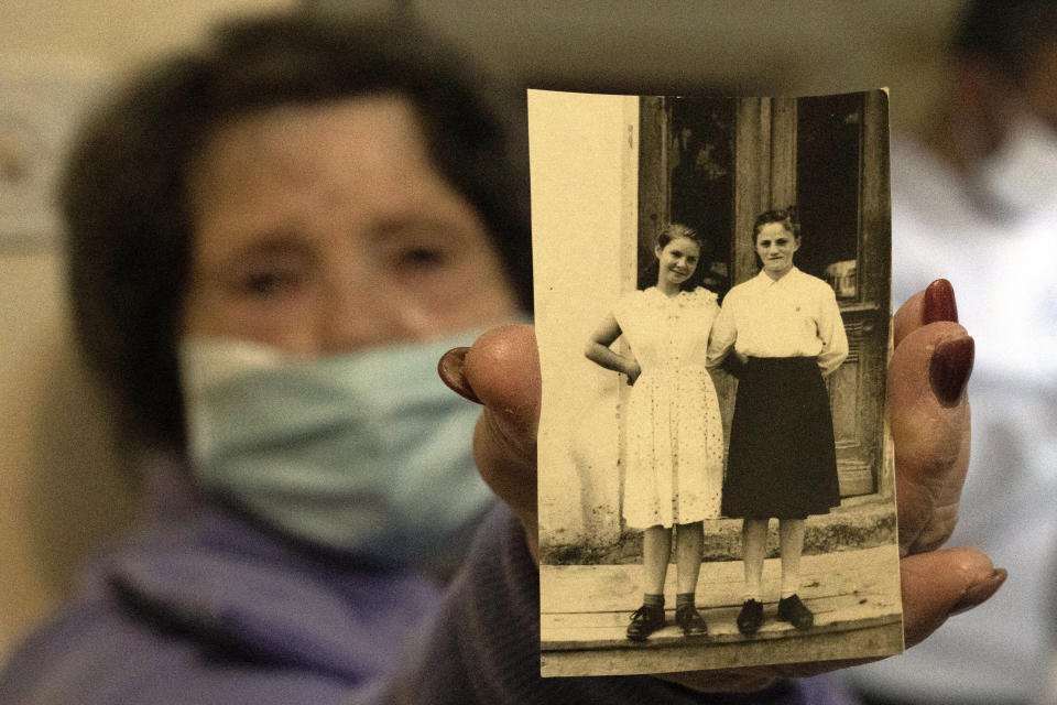 Holocaust survivor Freida Rovenchim holds an undated family photo showing herself, left, in Jerusalem, Wednesday, Jan. 26, 2022. Several dozen impoverished elderly Israelis, among them Holocaust survivors, received food donations from the Chasdei Naomi charity, ahead of International Holocaust Remembrance Day on Thursday. (AP Photo/Maya Alleruzzo)