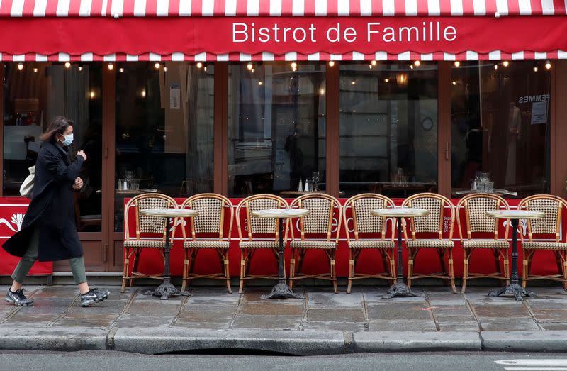 FILE PHOTO: A woman wearing a protective face mask walks past a restaurant in Paris