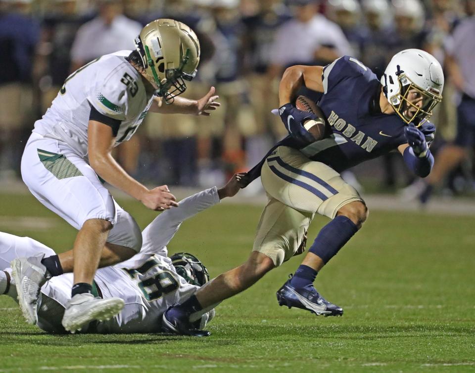 Hoban's Tyson Grimm breaks away from St. Vincent-St. Mary's Markelle Carter, center, and Mariano Mazzagatti for a second-quarter touchdown Friday, Oct. 8, 2021.