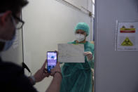 In this photo taken on Friday, May 8, 2020, internal medicine Sofia Prappa holds a paper with medical tests as medical student Nikolaos Katsanakis takes a photograph at the COVID-19 Clinic of Sotiria Hospital in Athens. Greece's main hospital for the treatment of COVID-19 is also the focus of a hands-on training program for dozens of medical students who volunteered to relieve hard-pressed doctors from their simpler duties while gaining a close peek at the front lines of a struggle unmatched in modern medical history. (AP Photo/Thanassis Stavrakis)