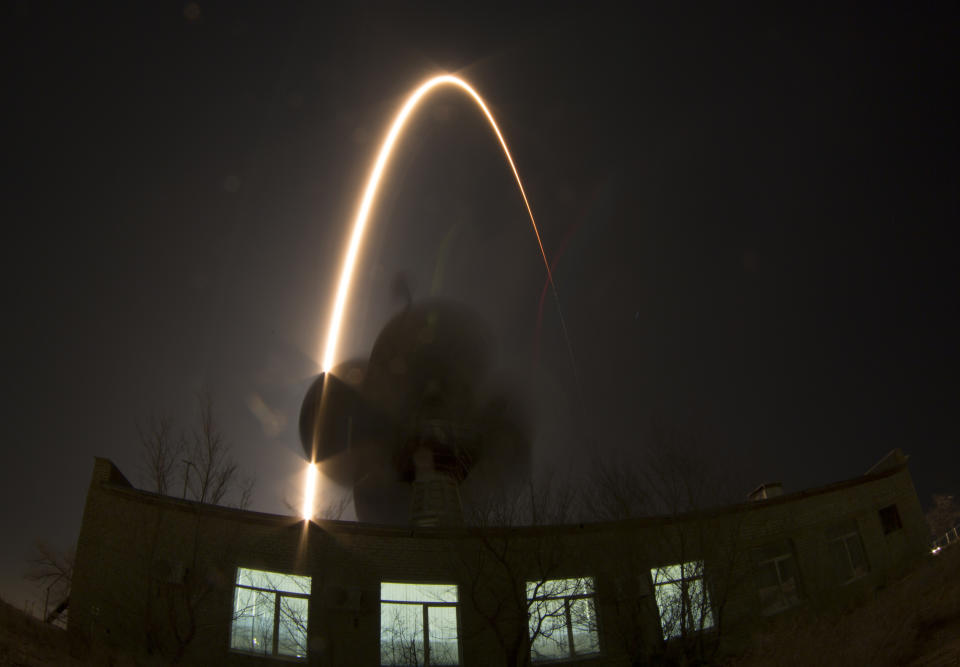 In this photo taken with a fisheye lens and long exposure, the Soyuz-FG rocket booster with Soyuz TMA-12M space ship carrying a new crew to the International Space Station (ISS) blasts off over an antenna at the Russian leased Baikonur cosmodrome, Kazakhstan, Wednesday, March 26, 2014. The Russian rocket carries U.S. astronaut Steven Swanson, Russian cosmonauts Alexander Skvortsov and Oleg Artemyev. (AP Photo/Dmitry Lovetsky)