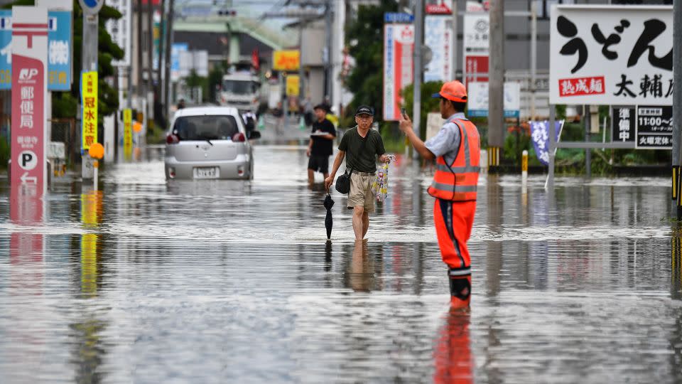 Residents maneuver through a flooded street in the city of Kurume, Fukuoka prefecture, on July 10, 2023. - Kazuhiro Nogi/AFP/Getty Images