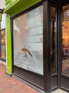 A broken storefront window outside Burlington business Thorn + Roots.