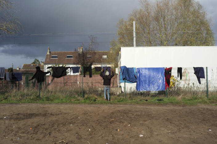 A migrant hangs his laundry on a fence in a makeshift camp outside Calais, northern France, Saturday, Nov. 27, 2021. At the makeshift camps outside Calais, migrants are digging in, waiting for the chance to make a dash across the English Channel despite the news that at least 27 people died this week when their boat sank a few miles from the French coast. (AP Photo/Rafael Yaghobzadeh)