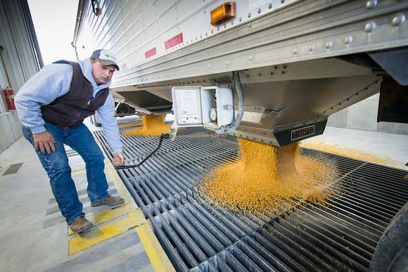 Worker watching grain drop into a milling facility.