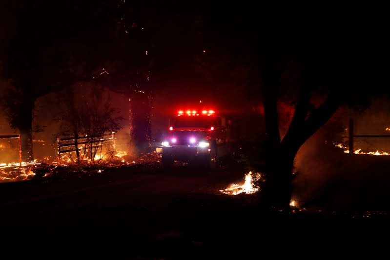 A fire engine drives on a road with active fire on both sides during the wind-driven Kincade Fire in Santa Rosa, California