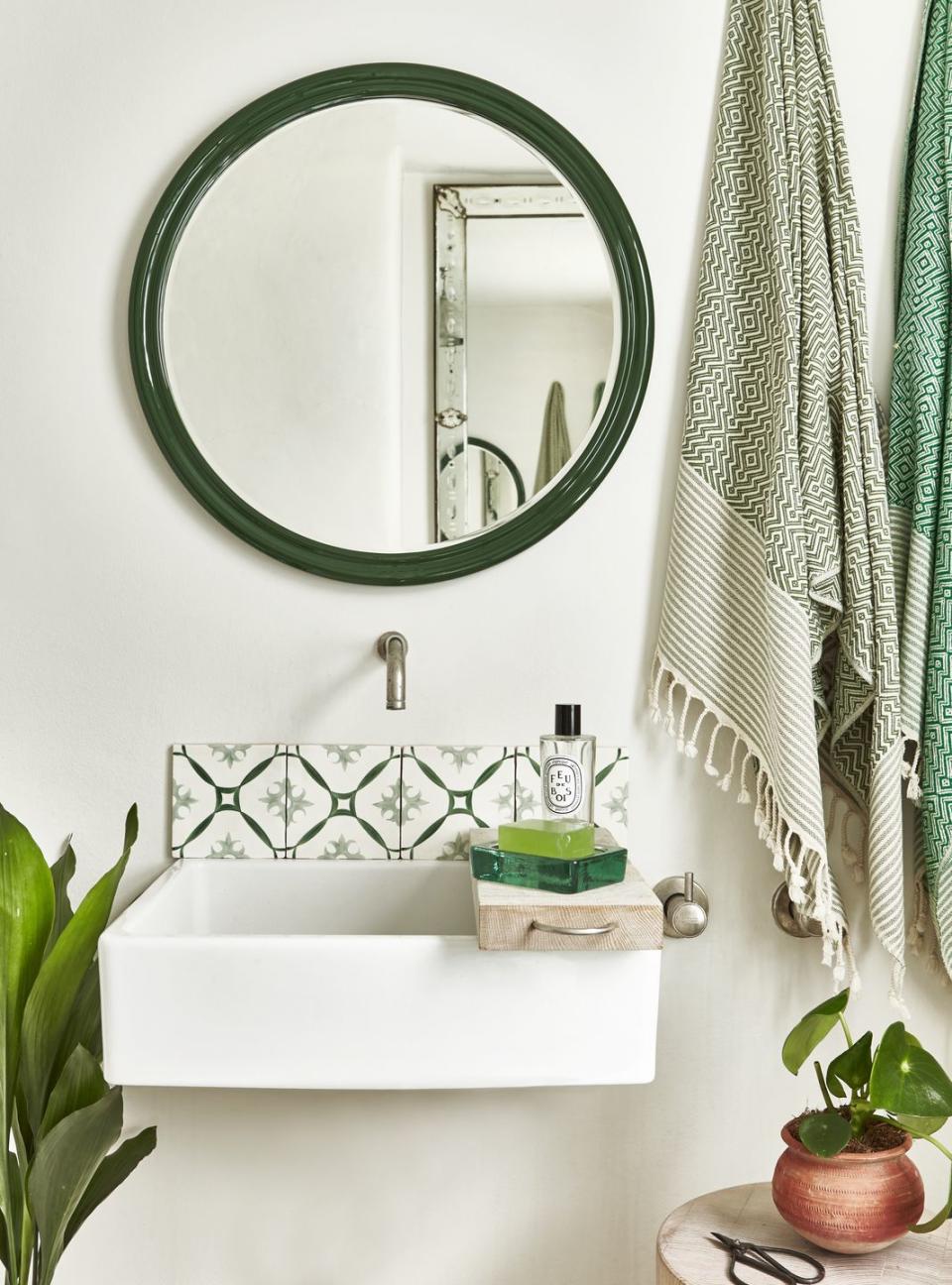 bathroom sink with plants, towels and green tiles