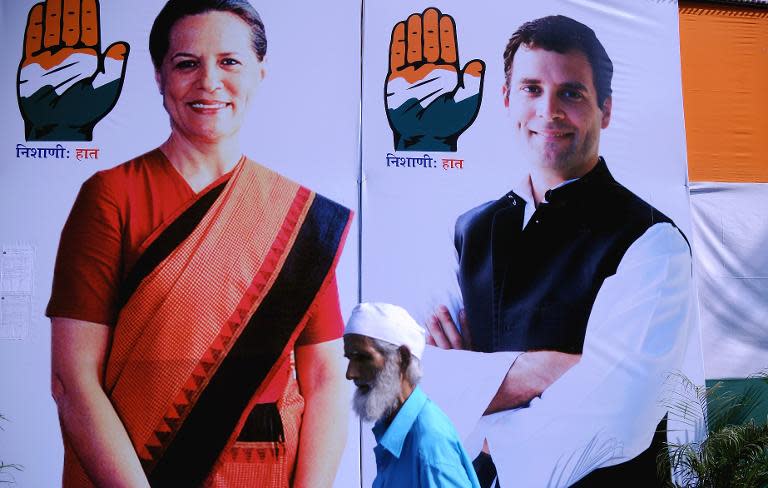 An Indian resident walks past a Congress Party election office bearing images of party president Sonia Gandhi (L) and her son and party vice president Rahul Gandhi in Mumbai on April 15, 2014