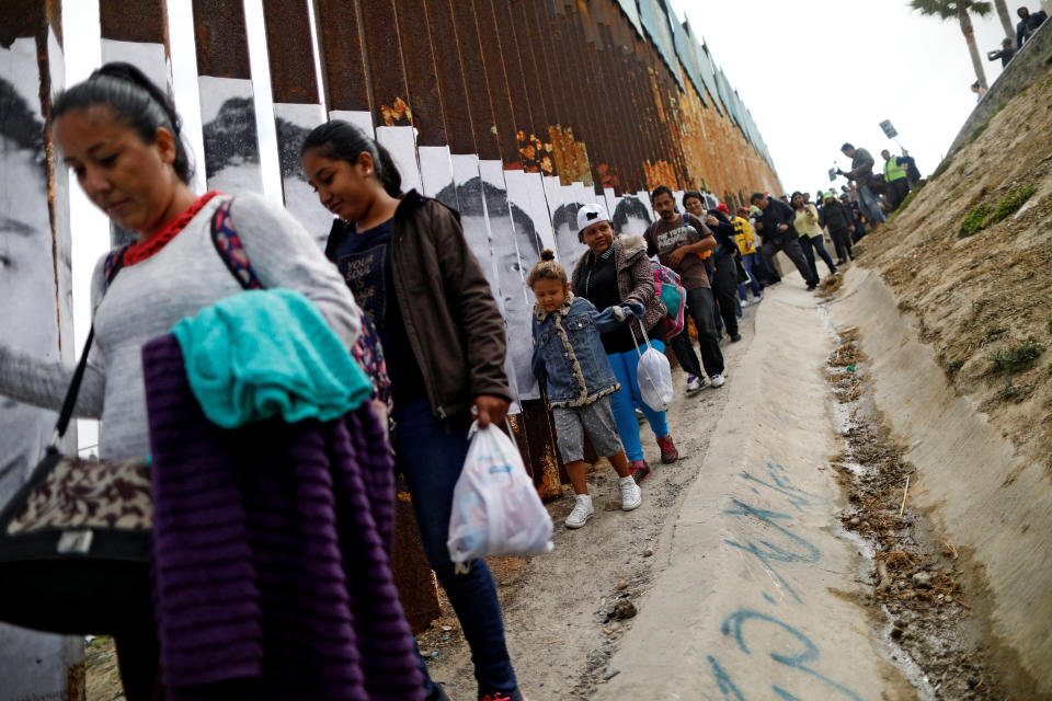 Members of&nbsp;the&nbsp;caravan that traveled across Mexico&nbsp;walk next to the border fence.