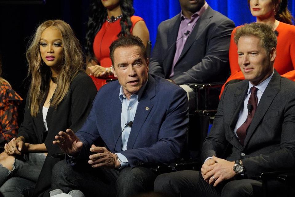 In this Friday, Dec. 9, 2016 photo provided by NBC, Tyra Banks, from left, Arnold Schwarzenegger, Patrick Knapp Schwarzenegger attend a press junket for "The New Celebrity Apprentice," in Los Angeles. Schwarzenegger, star of the new version of the television show, is unfazed that President-elect Donald Trump has retained a producer's stake in the show. Schwarzenegger said Friday that it's just business, comparable to his situation when he became California's governor and retained a screen credit and kept earning royalties for the "Terminator" movie. (Paul Drinkwater/NBC via AP)