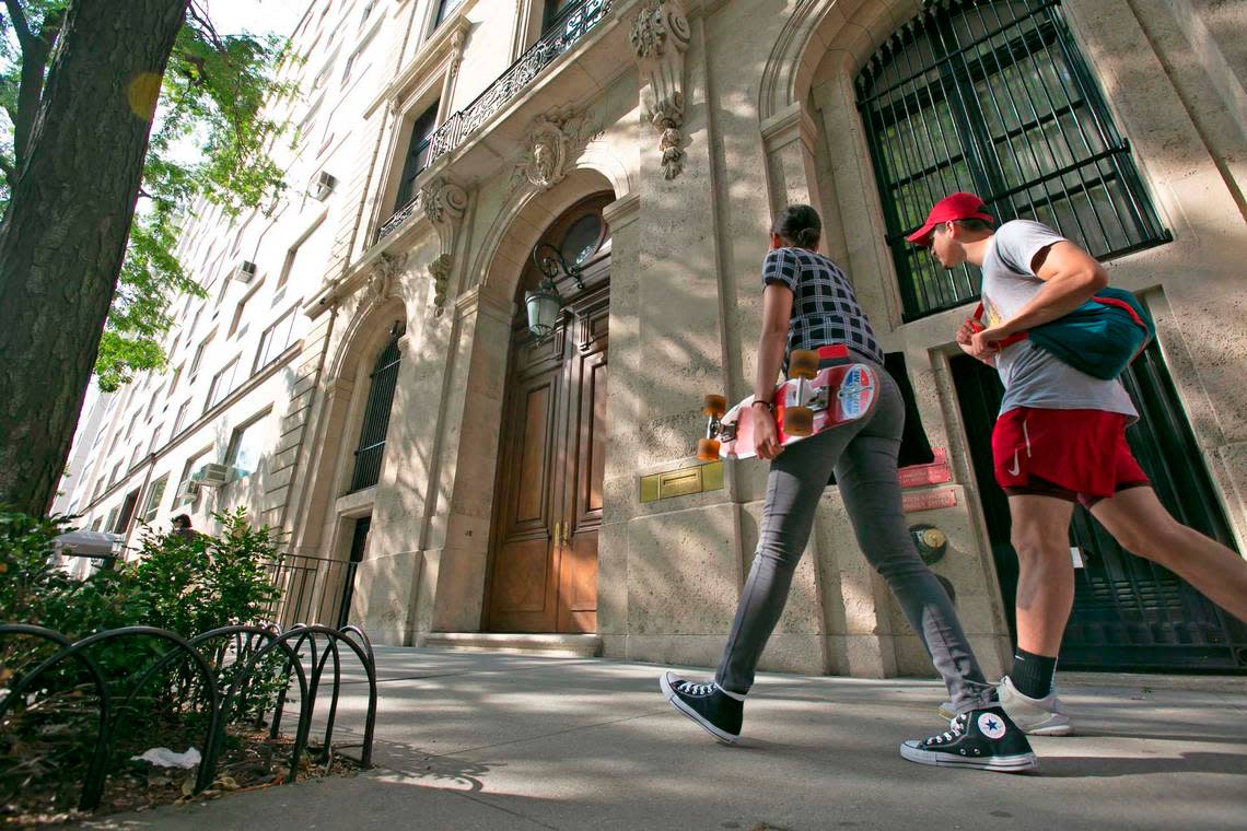 People walk by the Upper East Side New York estate of deceased mulitmillionaire Jeffrey Epstein. Damage on the front doors of Epstein’s residence was caused by agents serving a search warrant following Epstein’s arrest at a nearby New Jersey airport Saturday July 6, 2019 .