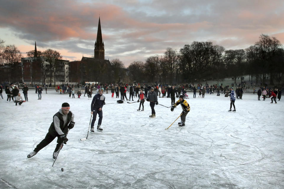 People play ice hockey as the sun sets on a frozen pond in Queen's Park, Glasgow, Scotland, Sunday Jan. 3, 2021. (Andrew Milligan/PA via AP)