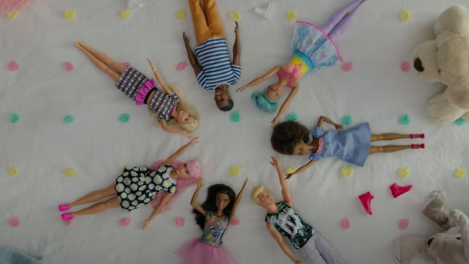 A circle of different Barbie dolls lying on their backs.