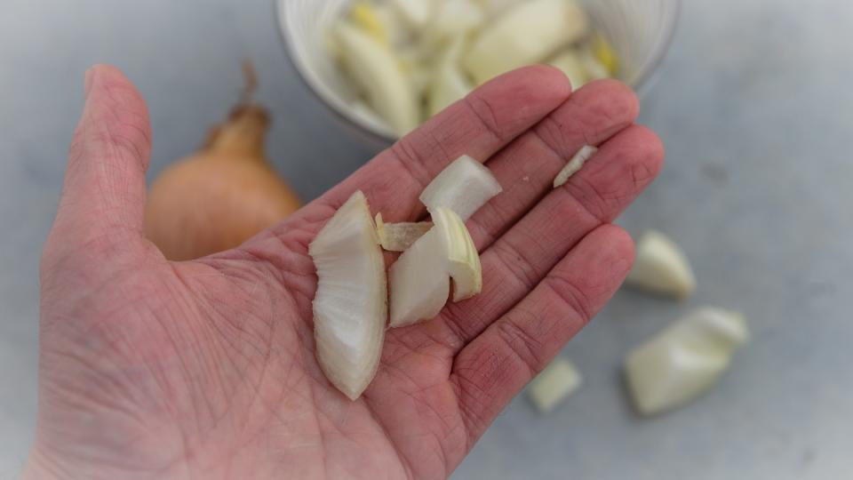 a hand holding sliced pieces of an onion  as one of the surprising uses for onions