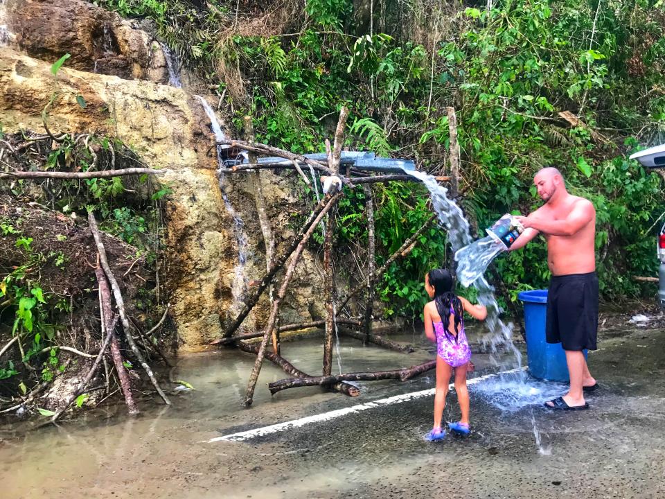 <p>A young girl and her father rinse off in naturally flowing water from the side of a mountain in Ciales, Puerto Rico on Oct. 11, 2017. (Photo: Caitlin DIckson/Yahoo News) </p>