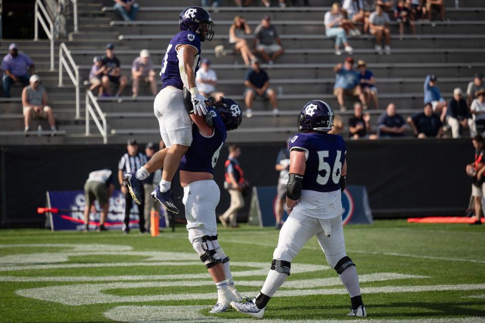 Holy Cross' C.J. Hanson lifts Jordan Fuller while Christo Kelly looks on after Fuller scored his fourth touchdown during a game earlier this season at Fitton Field.