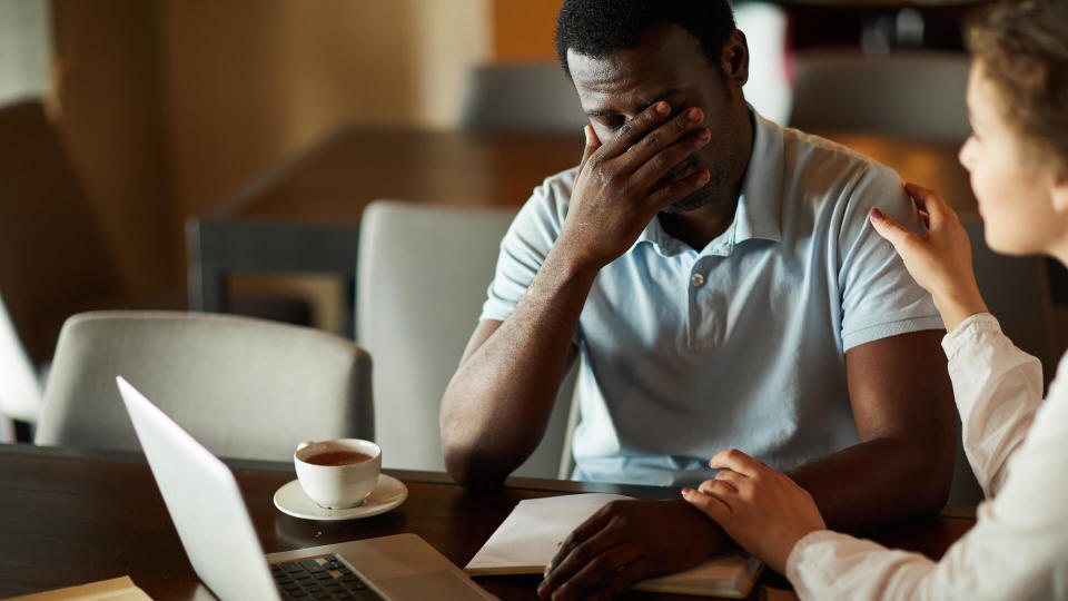 Young businessman in trouble sharing his problem with female colleague who comforting him.