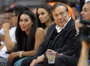 In this photo taken on Friday, Oct. 25, 2013, Los Angeles Clippers owner Donald Sterling, right, and V. Stiviano, left, watch the Clippers play the Sacramento Kings during the first half of an NBA basketball game in Los Angeles. The NBA is investigating a report of an audio recording in which a man purported to be Sterling makes racist remarks while speaking to Stiviano. NBA spokesman Mike Bass said in a statement Saturday, April 26, 2014, that the league is in the process of authenticating the validity of the recording posted on TMZ's website. Bass called the comments "disturbing and offensive." (AP Photo/Mark J. Terrill)