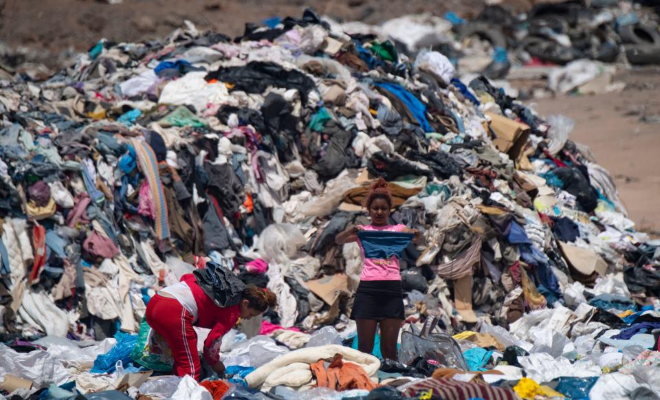 Women search for used clothes amid tons discarded in the Atacama desert, in Alto Hospicio, Iquique, Chile, on September 26, 2021.  EcoFibra, Ecocitex and Sembra are circular economy projects that have textile waste as their raw material. The textile industry in Chile will be included in the law of Extended Responsibility of the Producer (REP), forcing clothes and textiles importers take charge of the waste they generate.  / AFP / MARTIN BERNETTI