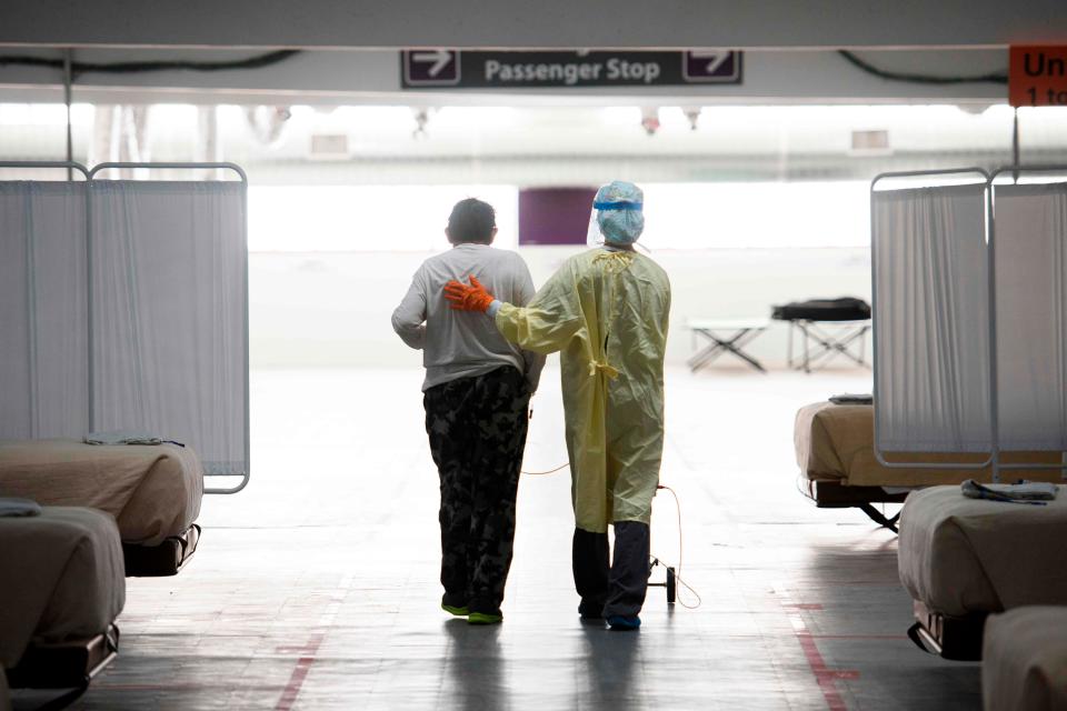 A nurse supports a patient as they walk in the COVID-19 alternative care site, built into a parking garage, at Renown Regional Medical Center, Dec. 16, 2020, in Reno, Nev. Renown Health converted two floors of a parking garage into an alternative care site for COVID-19 patients to increase hospital capacity amid a surge in cases, allowing other facilities to be used for patients in more serious condition.