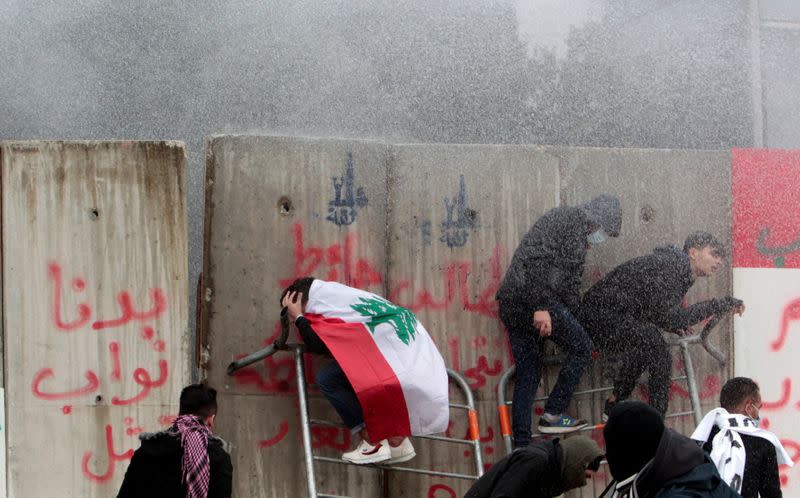 Demonstrators are sprayed with a water cannon during a protest seeking to prevent MPs and government officials from reaching the parliament for a vote of confidence, in Beirut