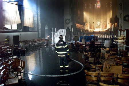 FILE PHOTO: New York City firefighter Captain William Fitchett of Ladder 163 stands in water as he examines the main naive of the Cathedral of St. John the Divine, on Manhattan's upper West side, December 18, 2001. REUTERS/Mike Segar/File Photo