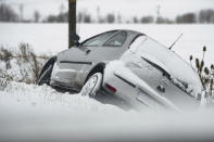 A car lies in a ditch on a snow-covered country road in the district of Goettingen, Germany, Sunday, Feb. 7, 2021. (Swen Pfoertner/dpa via AP)
