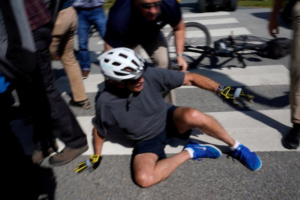 Joe Biden falls to the ground after riding up to members of the public during a bike ride in Rehoboth Beach, Delaware, US (Reuters)