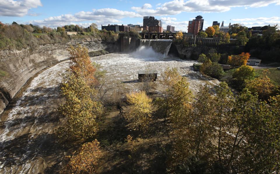 Fall colors surround High Falls on the Genesee River as it makes its way through the center of Rochester Monday, Nov. 1, 2021.  The photo is taken looking southward from the Pont de Rennes Bridge over the river. 