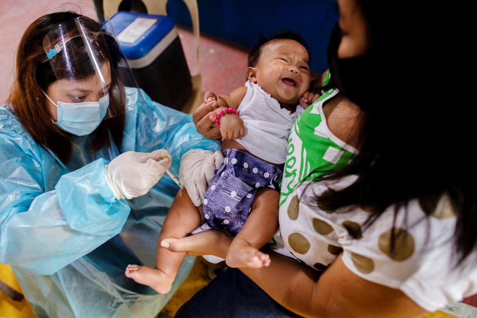 A nurse wearing personal protective equipment (PPE) for protection against the coronavirus disease (COVID-19) gives routine vaccines to a baby held by his mother in a local health center in Manila, Philippines January 27, 2021. Picture taken January 27, 2021. REUTERS/Eloisa Lopez